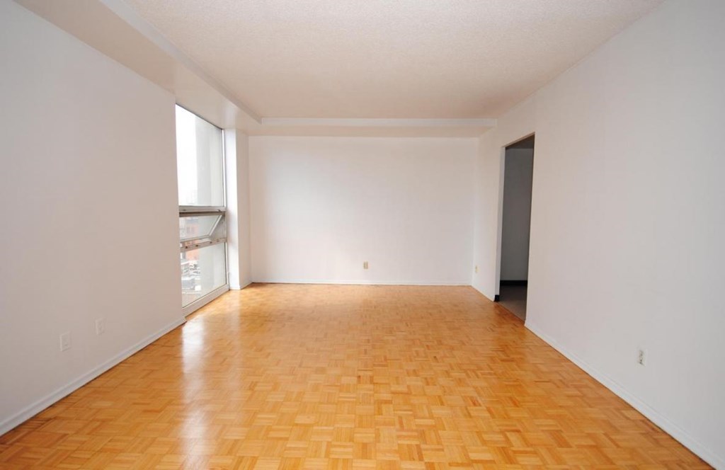Empty room with wooden flooring and white walls.