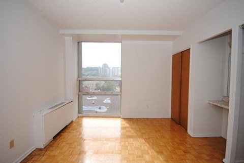 A room with wooden floors and a large window overlooking a parking lot.
