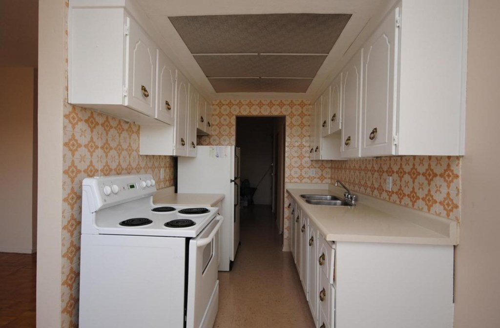 A kitchen with a white stove and cabinets.