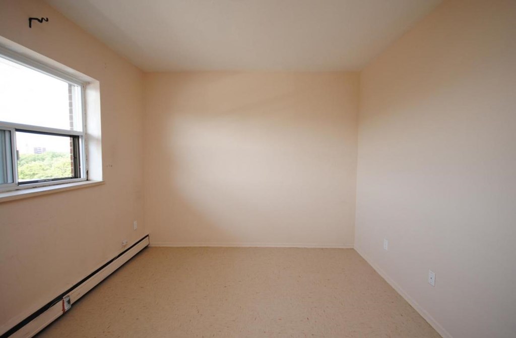 A room with a window and a wall with a switch.