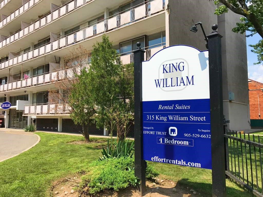 A sign for King William Rental Suites stands in front of a building.