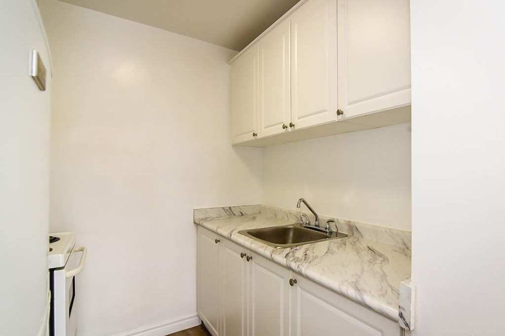 A kitchen with a marble countertop and white cabinets.
