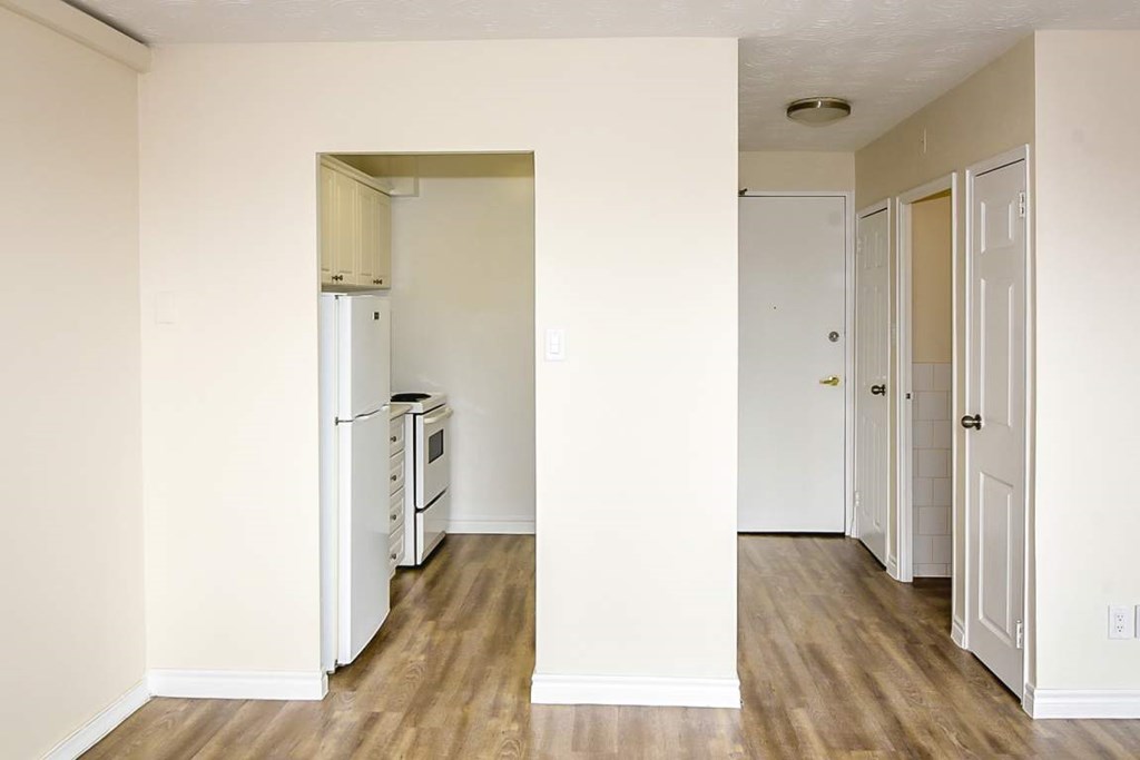 A kitchen with white appliances and wood floors.