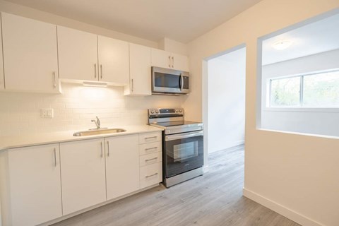 A kitchen with white cabinets and a microwave above the stove.
