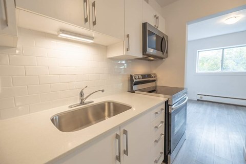 A kitchen with white cabinets and a stainless steel sink.