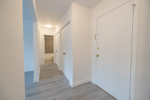 A long hallway with white walls and wood flooring.