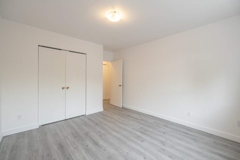 A room with a white wall and a grey floor with a white door.