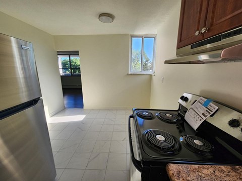 A kitchen with a stove, refrigerator, and a window.