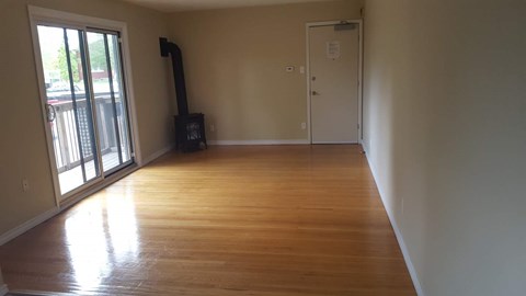 A room with wooden flooring and a door on the right side.