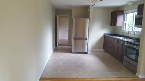 A kitchen with a refrigerator and wooden floors.
