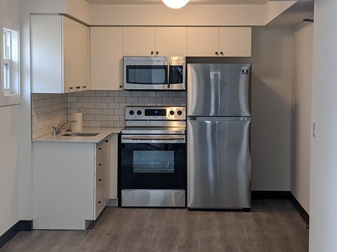 A modern kitchen with a stainless steel refrigerator, oven, and microwave.