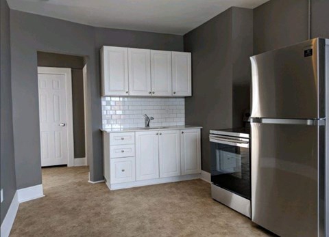 A kitchen with a stainless steel refrigerator and white cabinets.