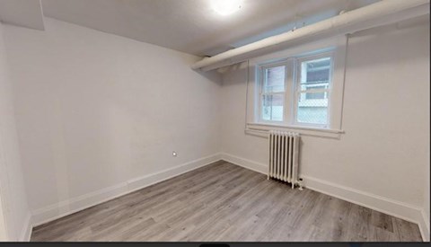 A room with a window and a radiator on the floor.