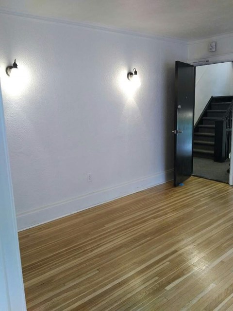 A room with wooden floors and two wall lights.