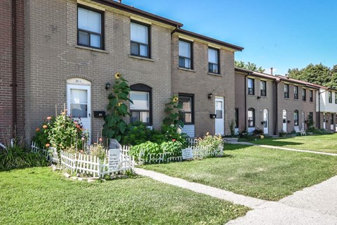 A row of houses with a white picket fence in front.
