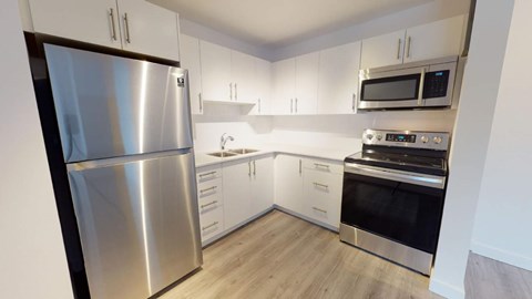 A kitchen with a stainless steel refrigerator, microwave, and oven.