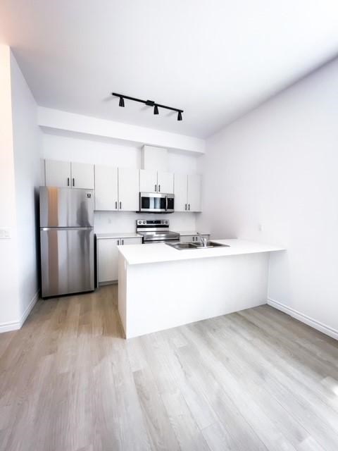 A kitchen with a refrigerator, microwave, and oven.