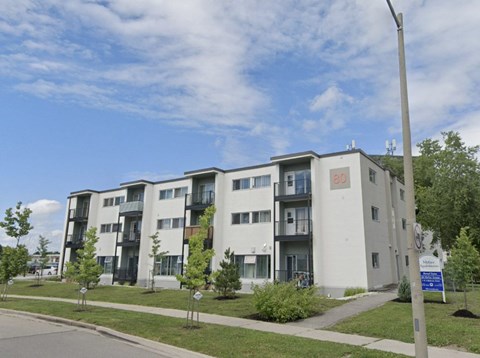 A modern apartment building with balconies and a blue sign in front.