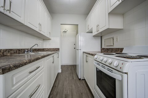 A kitchen with white cabinets and a granite countertop.