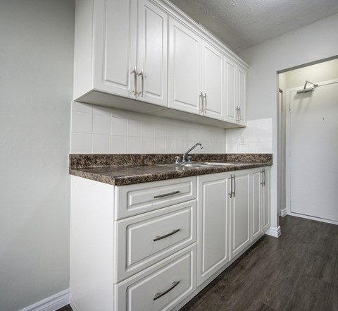 A kitchen with white cabinets and a granite countertop.