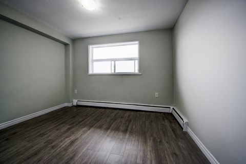 A room with a window and wooden flooring.