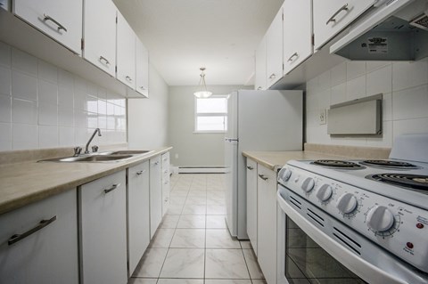 A kitchen with white cabinets and a stove top oven.