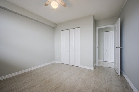 A room with a white door and a ceiling fan.