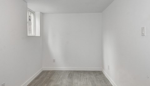 A room with a window and a wooden floor.