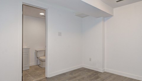 A bathroom with a toilet and a doorway leading to another room.