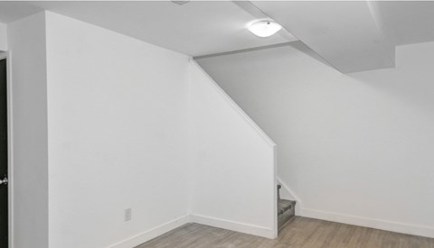A white room with a staircase and a light on the ceiling.