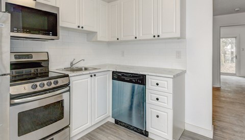A modern kitchen with white cabinets and stainless steel appliances.
