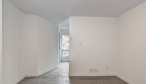 A room with white walls and a doorway leading to another room.
