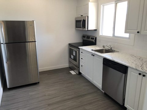 A kitchen with a refrigerator, microwave, dishwasher, and sink.