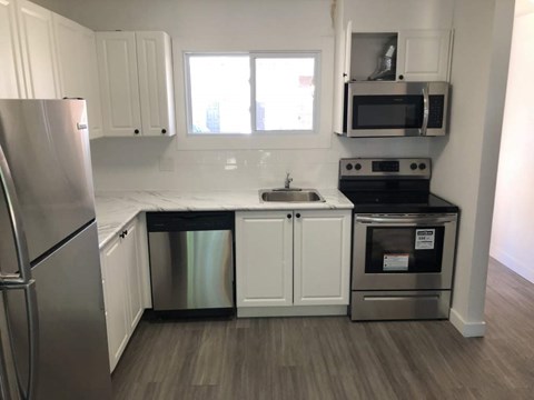 A kitchen with white cabinets and a stainless steel refrigerator.