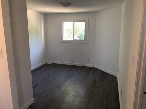 A room with a window and wooden flooring.