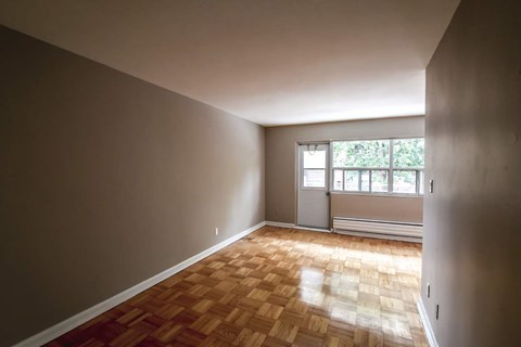 A room with wooden flooring and a window with blinds.