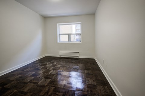 A room with a window and a radiator on the floor.