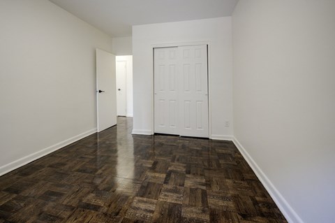 A room with a white door and a wooden floor.