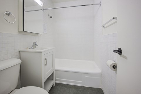 A white bathroom with a toilet, sink, and bathtub.