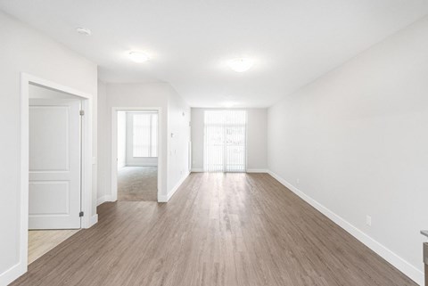 A spacious room with wooden floors and white walls.
