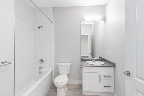 A white bathroom with a toilet, sink, and bathtub.