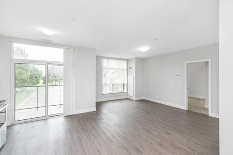 A spacious room with wooden flooring and large windows.