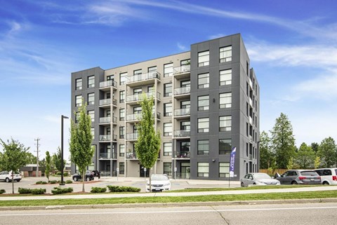 A modern apartment building with balconies and a flag on the front.