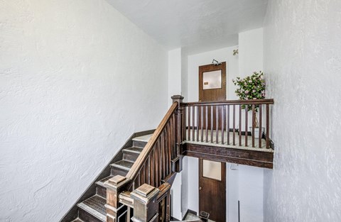 A wooden staircase with a metal railing and a door at the bottom.