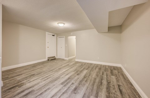 A room with wooden flooring and two doors.