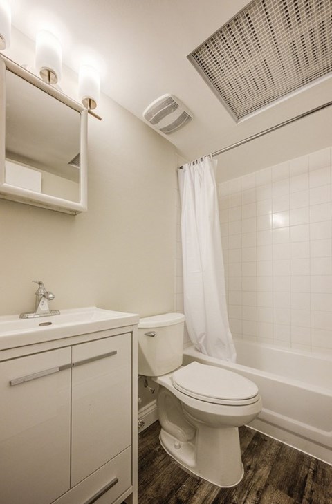 A white toilet in a bathroom with a white shower curtain.