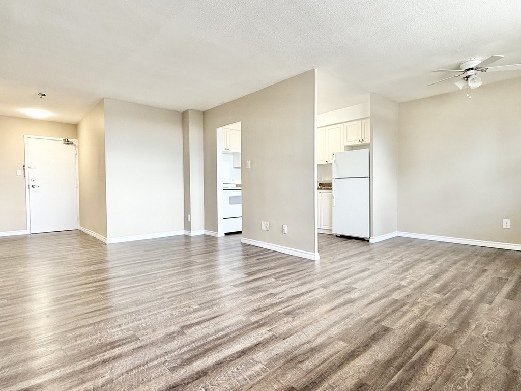 A spacious room with wood flooring and a ceiling fan.