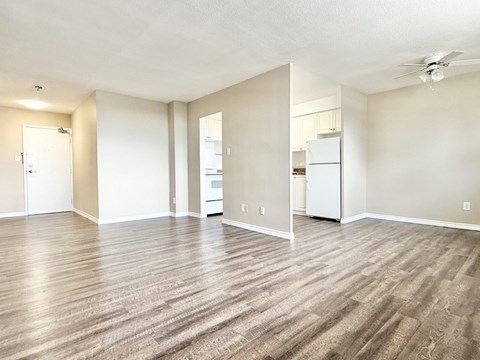 A spacious room with wood flooring and a ceiling fan.