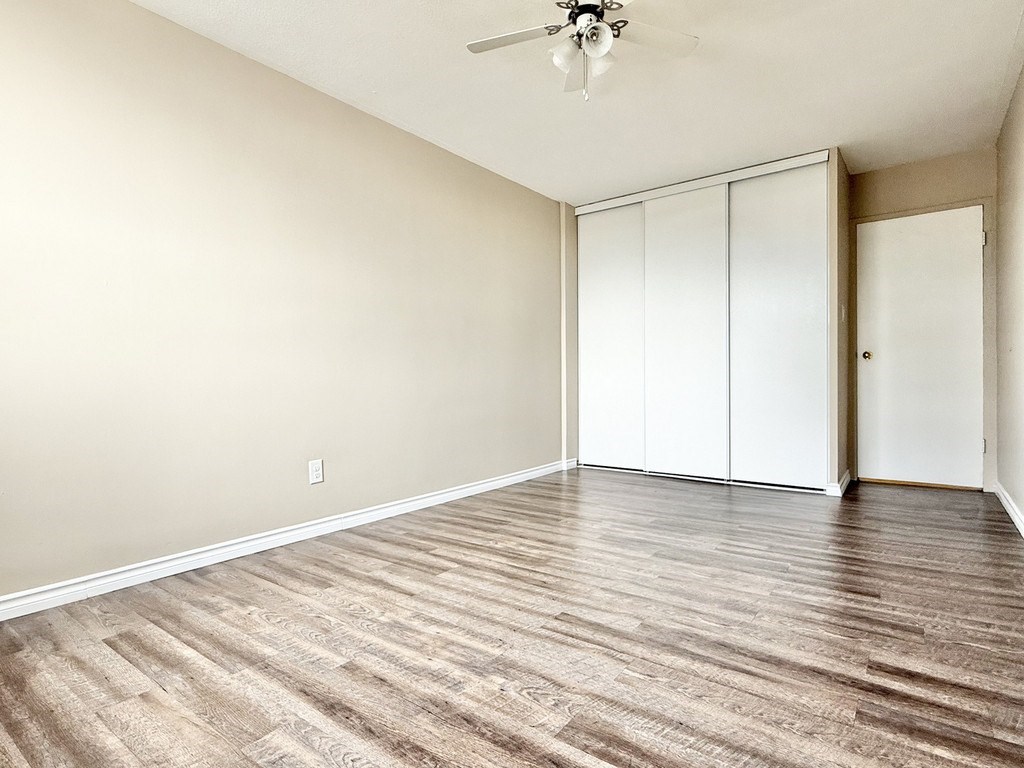 A room with a ceiling fan and wood flooring.