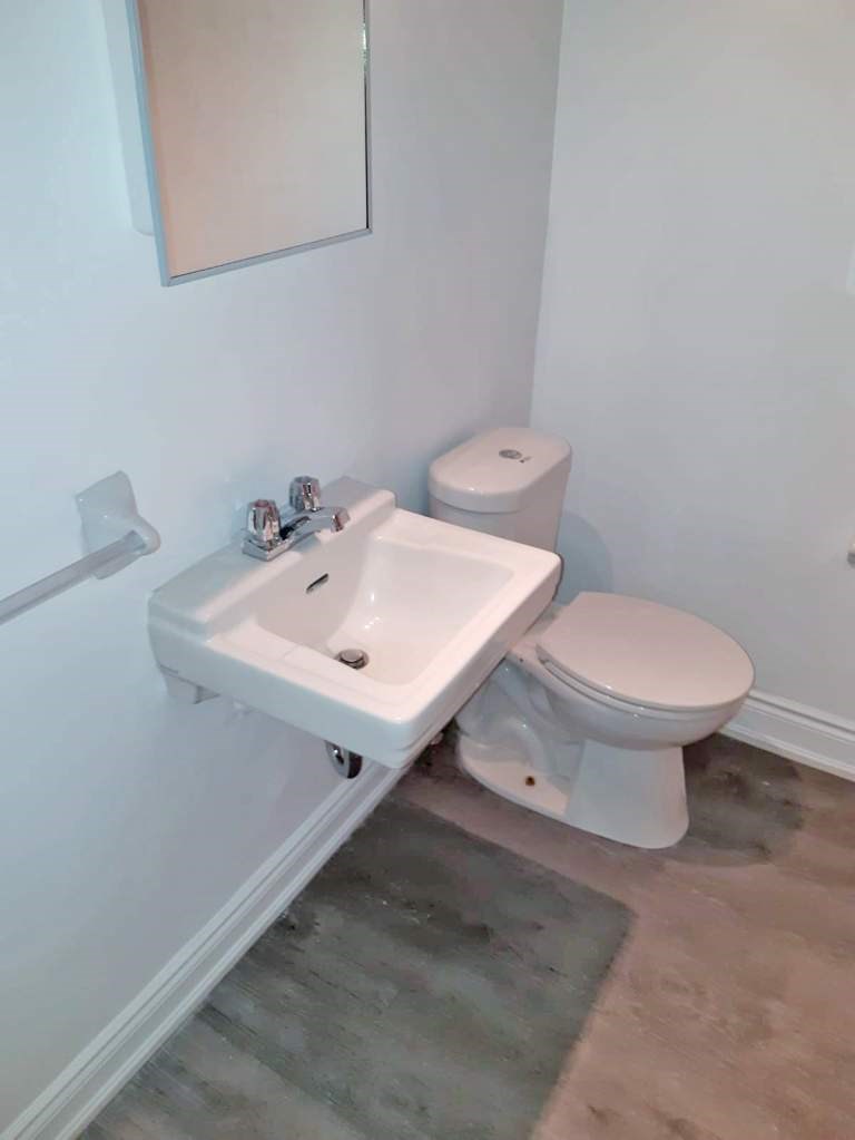 A white toilet and sink in a small bathroom.